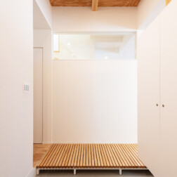 玄関の天井はこだわりのひとつ。土間と梁をみせた木の天井が趣きあります。造作のシューズクローゼットは収納力抜群です。正面のすのこは、リビングとトイレをつなぎます。