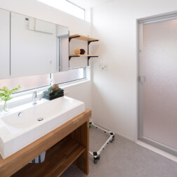 洗面台は扉をつけずオープンタイプで造作しました。こだわりの三面鏡の上下にFIX窓と引違窓で光を取りこみます。