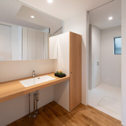 シンプルでオープンな洗面台を設置した洗面スペースと白を基調とした脱衣室。とても清潔感のある空間です。それぞれが独立しているので、プライバシーにも配慮した設計になっています。たっぷり入る収納も日用品の置き場所に最適です。