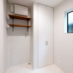 天井まである収納は、収納力抜群です。白を基調としながら、さりげなくタイル調のクロスを採用し、脱衣場もおしゃれ空間になりました。