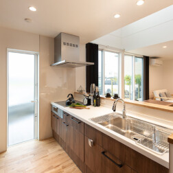 LDK - リビングには天井まである大きな窓。大きな窓からは、立地条件からの特権で自然をいっぱい感じる景色を望めます。オークの床材、キッチンもオーク色、またバーチカルブラインドもブラウン系を選びシンプルにまとめたインテリアの中で、アクセントとなるのがマリメッコのカーテン。お施主様らしさがでて、素敵です。キッチンはLIXILアレスタを採用。