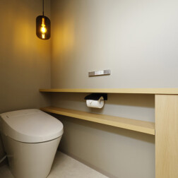 トイレ空間はクロスも照明も落ち着いた色合いでまとめました。奥様のご要望により、トイレ収納とカウンターを造作。