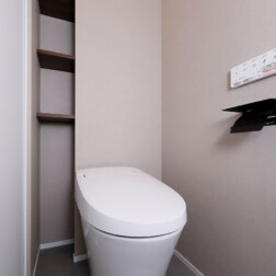 トイレ:サティスS(LIXIL)
落ち着いたカラーのクロスに、モルタル調のフロアタイルを合わせた空間。
背面には天井までの造作棚を設け、収納力も確保しました。